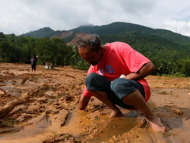 Seorang pria mencoba untuk menemukan sandalnya yang tertimbun lumpur setelah longsor di Desa Elangipitiya, Aranayaka, Sri Lanka (19/5). Ratusan warga dikabarkan hilang akibat tanah longsor tersebut. (REUTERS/Dinuka Liyanawatte)