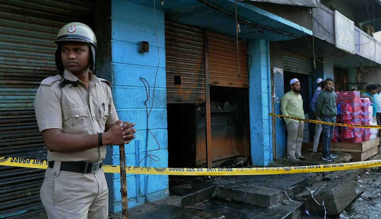 Seorang polisi berjaga di depan restoran yang terbakar di Bangalore, India (8/1). Polisi mengatakan sebuah arus listrik pendek yang menyebabkan kebakaran di Kailash Bar & Restoran di pusat teknologi selatan Bangalore. (AFP Photo/Manjunath Kiran)