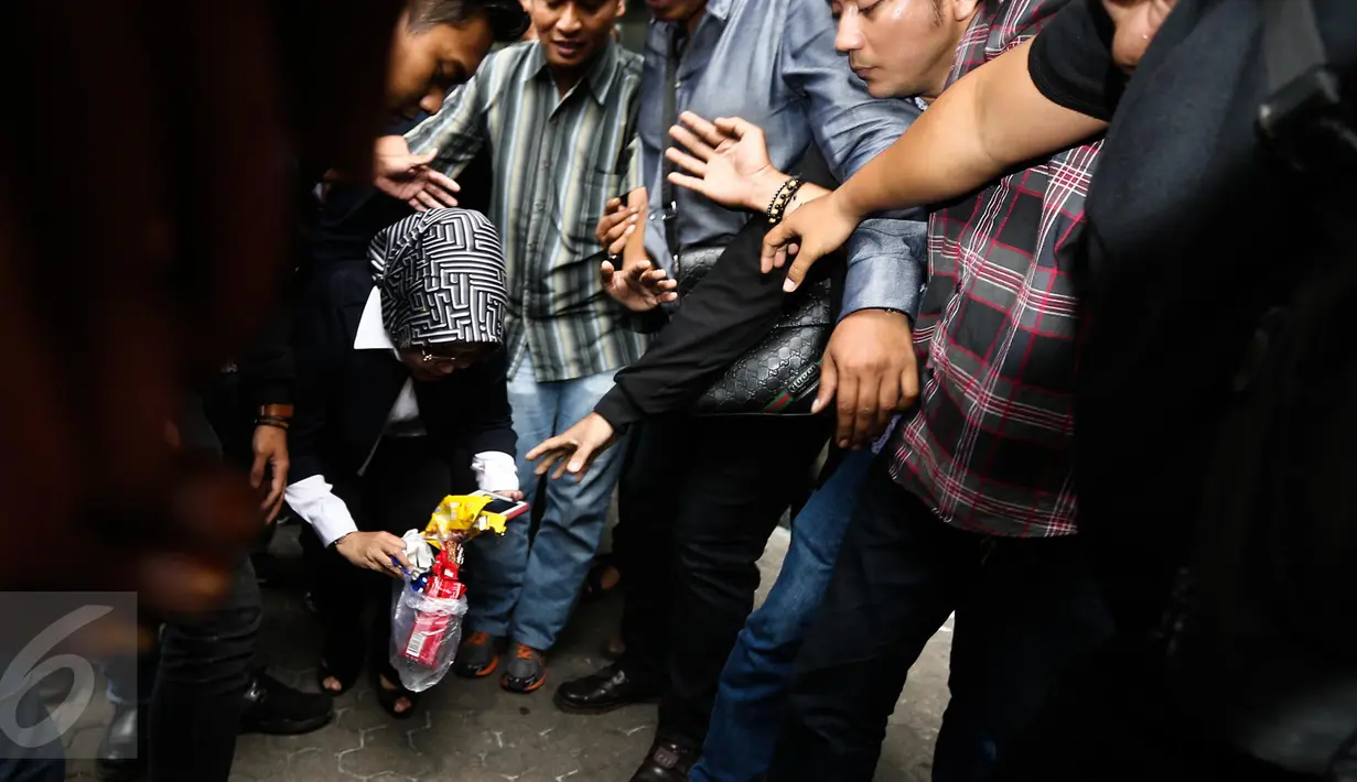 Sylviana Murni memungut sampah usai diperiksa Bareskrim di Gedung Ombudsman, Jakarta, Senin (30/1). Panggilan tersebut terkait pemeriksaan kasus dugaan korupsi pembangunan Masjid Al-Fauz. (Liputan6.com/Faizal Fanani)