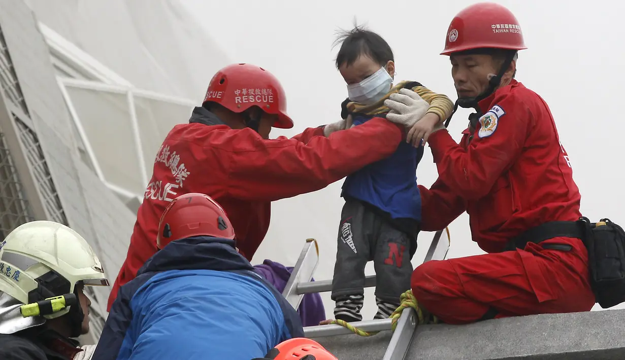 Petugas penyelamat mengevakuasi seorang anak yang selamat akibat gempa di Tainan, Taiwan Selatan (6/2). Gempa terjadi pukul 4 subuh tadi telah menghancurkan beberapa apartemen di kawasan Wei Guan, Tainan, Taiwan. (REUTERS/Stringer)