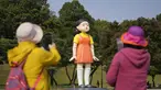 Pengunjung mengambil foto dekat boneka 'Younghee' yang menjadi maskot dalam serial Netflix asal Korea, Squid Game, di Olympic park, Seoul, Selasa (26/10/2021). Boneka setinggi empat meter atau 13 kaki itu, akan dipamerkan di taman tersebut selama tiga bulan. (AP Photo/Lee Jin-man)