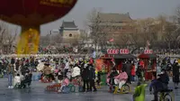 Pengunjung menikmati berseluncur di Danau Houhai beku yang ramai di dekat Menara Drum, latar belakang, di Beijing, Senin (30/1/2023). Orang-orang China menikmati Tahun Baru Imlek dan mengunjungi berbagai lokasi wisata di kota-kota di sekitar China setelah pencabutan pembatasan COVID-19 yang kejam bulan lalu, memungkinkan banyak aspek kehidupan normal kembali. (AP Photo/Andy Wong)