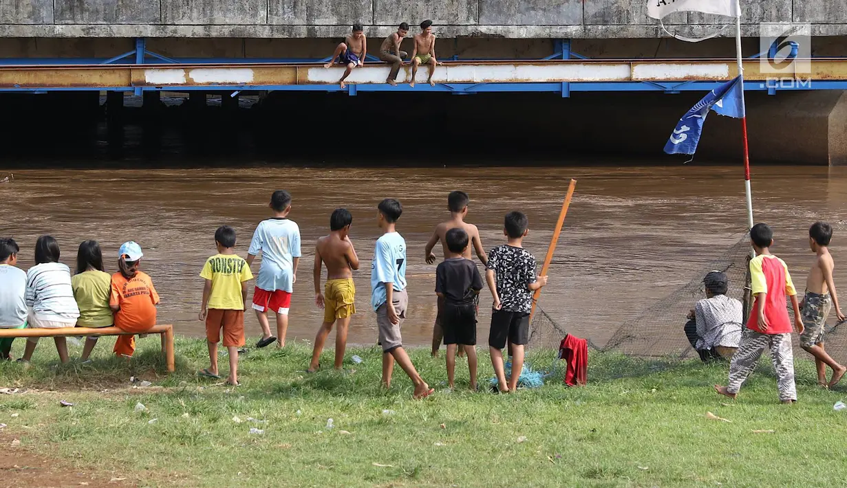 Anak-anak usai bermain sepak bola di bantaran Kanal Banjir Barat, Jakarta, Jumat (5/4). Tidak adanya lapangan menjadikan lokasi tersebut sebagai tempat bermain mereka, meskipun dalam kondisi seadanya. (Liputan6.com/Immanuel Antonius)