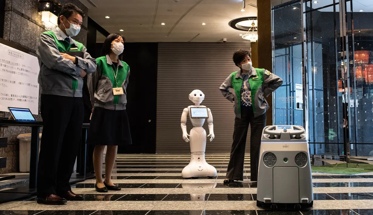 Gubernur Tokyo Yuriko Koike (kedua kanan) melihat robot Pepper (tengah) dan Whiz (kanan) saat mengunjungi hotel yang menjadi lokasi karantina pasien COVID-19 di Tokyo, Jepang, Jumat (1/5/2020). Beda dengan Pepper yang bertugas menyambut pasien COVID-19, Whiz bertugas bersih-bersih. (Philip FONG/AFP)