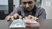 Pegawai menunjukkan uang rupiah dan dolar AS di salah satu gerai money changer di Jakarta, Senin (4/7/2022). Melansir data Refinitiv, hingga 4 Juni 2022 pukul 11:10 WIB rupiah melemah 0,15 persen ke Rp14.957 per USD 1. (merdeka.com/Iqbal S Nugroho)