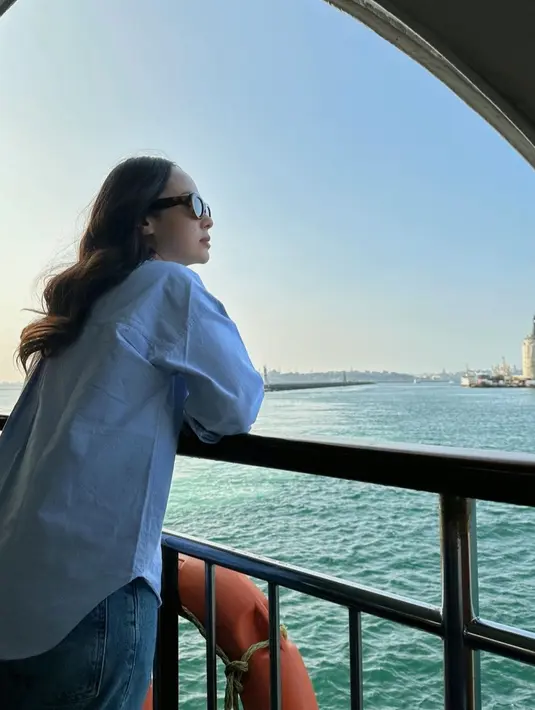 Pamela Bowie terlihat sedang memandang laut yang begitu indah. Penampilannya kala itu terlihat cantik dengan kemeja denim yang dipadukan dengan celana jeans serta kaca mata hitam
