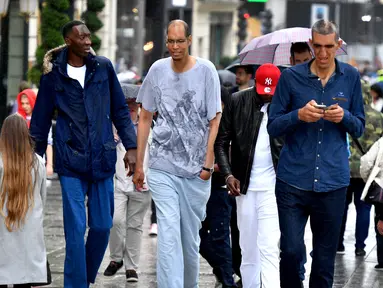 Abdramane Dembel dari Pantai Gading (2,35 meter), Brahim Takioullah dari Prancis (2,46 meter) dan Arshavir Grigoryan dari Armenia (2,33 meter) berjalan di tengah keramaian ketika orang tertinggi sedunia bertemu di Paris, 1 Juni 2018. (AFP/GERARD JULIEN)