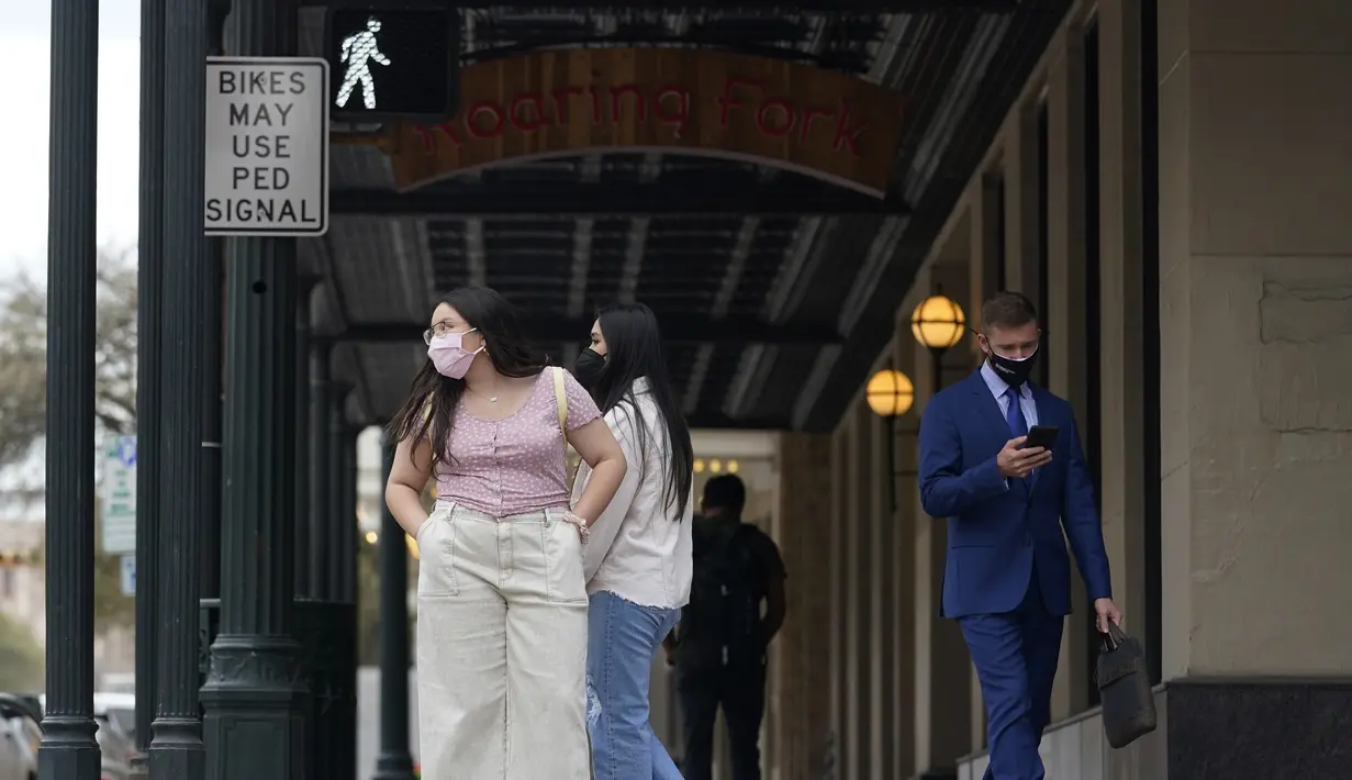 Pejalan kaki yang mengenakan masker untuk meminimalisir penyebaran Covid-19 berjalan melintasi pusat kota Austin, Texas, Selasa (9/3/2021). Mandat Gubernur Texas Greg Abbott yang mencabut keharusan mengenakan masker di negara bagiannya akan berlaku penuh mulai 10 Maret ini. (AP Photo/Eric Gay)