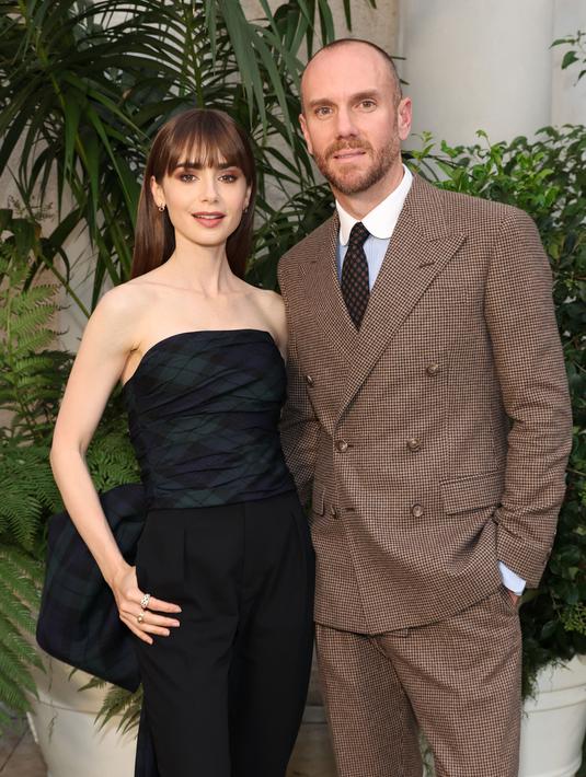 Lily Collins bersama suaminya Charlie McDowell berpose saatmenghadiri Ralph Lauren SS23 Runway Show di The Huntington Library, Art Collections, and Botanical Gardens di San Marino, California pada 13 Oktober 2022. Dia juga mengenakan jam tangan emas halus yang cocok dengan anting-anting melingkar bertabur menghiasi wajahnya. (Amy Sussman/Getty Images/AFP)