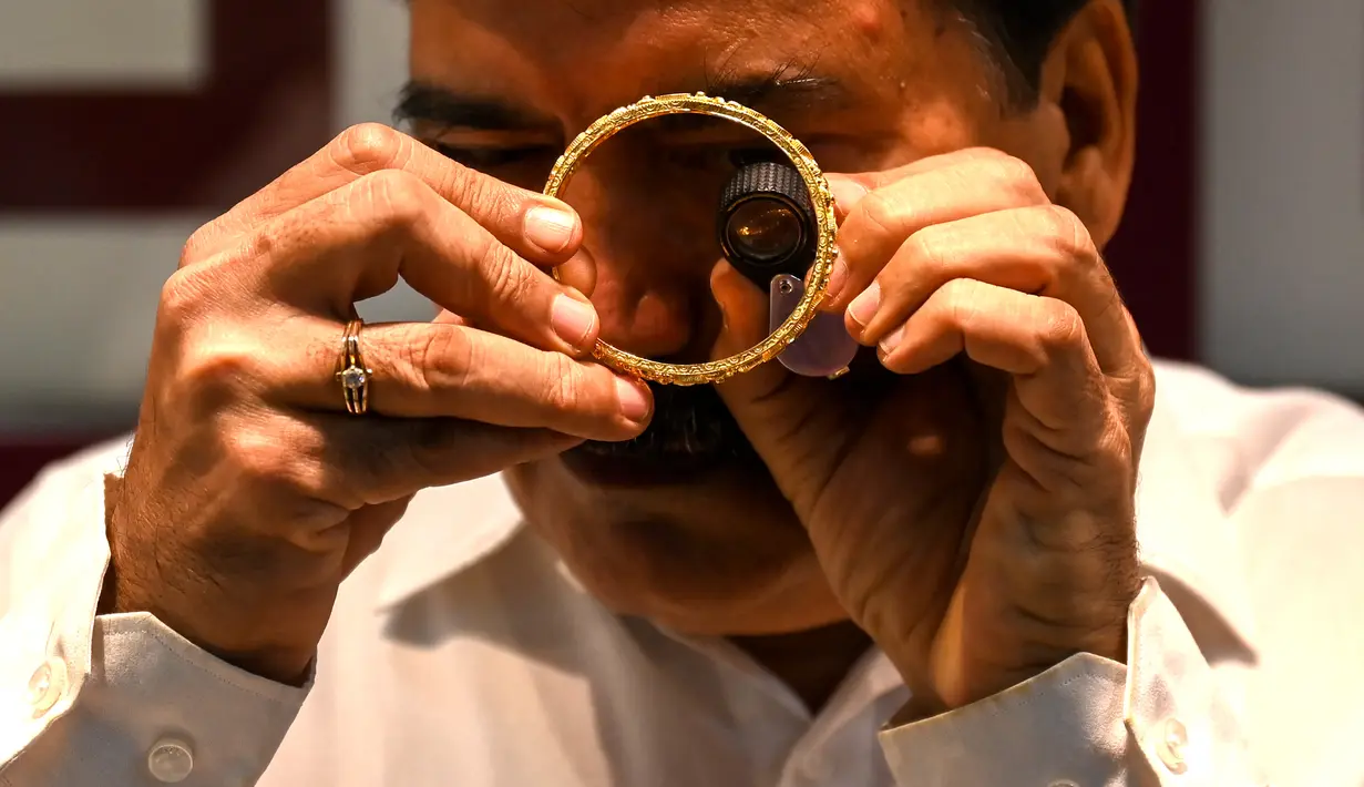 Gambar diambil pada 11 Agustus 2021 menunjukkan seorang manajer toko perhiasan memeriksa gelang emas di Mumbai, India. Putus asa mendapatkan uang tunai, banyak keluarga dan usaha kecil menjual perhiasan emas sebagai jaminan untuk mendapatkan pinjaman jangka pendek. (Punit PARANJPE/AFP)