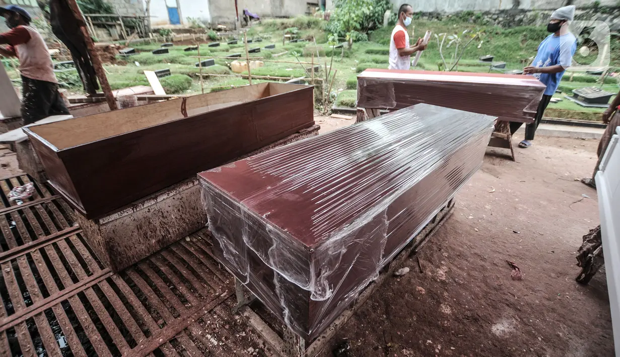 Pekerja menyelesaikan pembuatan peti jenazah untuk pasien Covid-19 di TPU Pondok Kelapa, Jakarta, Selasa (13/7/2021). Menurut pekerja, dalam sehari mampu membuat hingga 50 peti jenazah dari ratusan pesanan dari pihak rumah sakit, baik di Jakarta maupun luar kota. (merdeka.com/Iqbal S Nugroho)