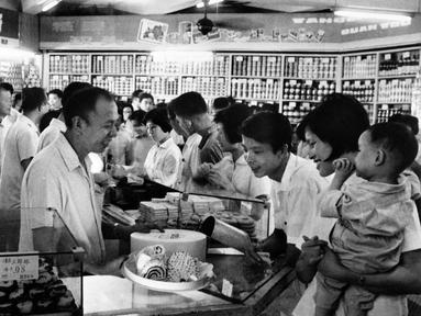 Pekerja melayani pelanggan di sebuah toko kue selama jam sibuk di Shanghai, China pada 24 September 1974. (AFP Photo)