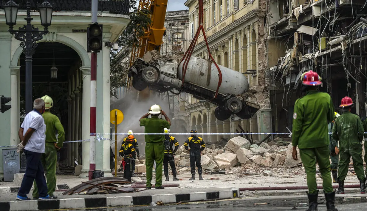 <p>Petugas pemadam kebakaran menyemprot truk tangki dengan air untuk mendinginkannya saat mereka memindahkannya dari lokasi ledakan mematikan yang menghancurkan Hotel Saratoga di Havana, Kuba, 6 Mei 2022. Ledakan kuat yang diduga disebabkan oleh kebocoran gas alam menewaskan 18 orang dan melukai puluhan orang. (AP Photo/Ramon Espinosa)</p>