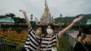 Pengunjung yang mengenakan masker berpose untuk foto di Disneyland Hong Kong pada Jumat (25/9/2020). Setelah dibuka dan tutup kembali, Disneyland Hong Kong dibuka kembali untuk wisatawan. (AP Photo/Kin Cheung)