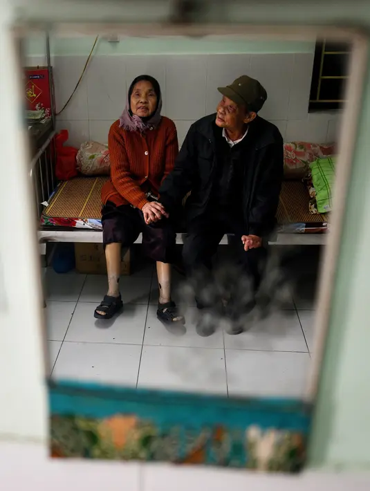 Penderita kusta Nguyen Thi Teo (kanan) dan istri Tran Huu Hoa (kiri) duduk di ranjang kompleks RS Van Mon Leprosy, Thai Binh, Vietnam, Kamis (10/1). Penderita kusta di Vietnam turun dari tahun ke tahun. (Manan Vatsyayana/AFP)