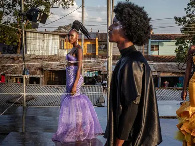 Para model berdiri di atas catwalk sambil memamerkan desain di peragaan busana selama Kibera Fashion Week di pemukiman informal Kibera di Nairobi, pada tanggal 15 Oktober 2023. (LUIS TATO/AFP)