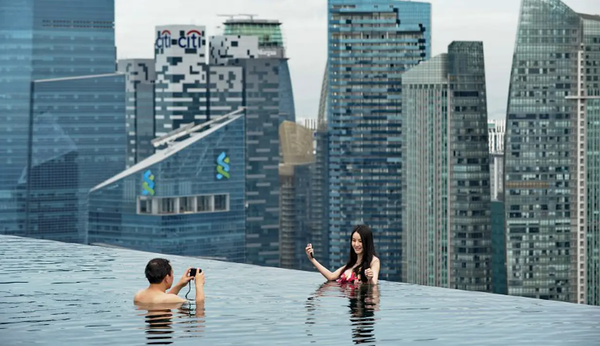 Sepasang suami istri mengambil foto mereka dari kolam renang atap dari Marina Bay Sands resort hotel yang menghadap cakrawala kota di Singapura, Selasa (20/05/2014) (AFP PHOTO/Roslan Rahman)