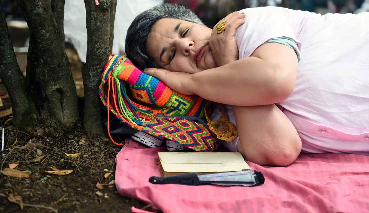 Seorang wanita Kolombia tidur saat berparade dalam merayakan Hari Kemalasan Sedunia di Itagui, dekat Medellin, Minggu (19/8). Perayaan hari relaksasi selama seharian itu telah digelar setiap tahun sejak 1985 di kota kecil tersebut. (AFP/JOAQUIN SARMIENTO)
