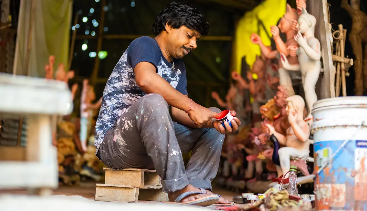 Seorang perajin menyiapkan cat warna saat membuat patung dewi Durga menjelang festival 'Durga Puja' di sebuah workshop di New Delhi, India, Rabu (14/10/2020). Durga Puja merupakan festival tahunan di Asia Selatan untuk memuja dewi Durga dari agama Hindu. (Photo by Jewel SAMAD / AFP)