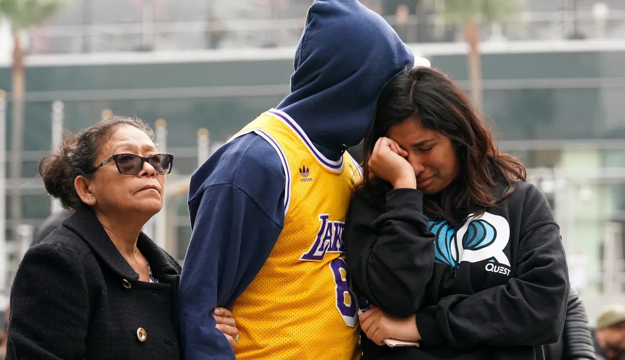 Fans LA Lakers tampak sedih usai Kobe Bryant meninggal dunia di Staples Center, Minggu (26/1/2020). Legenda basket NBA itu wafat dalam kecelakaan helikopter di Calabasas, California. (AFP/Rachel Luna)