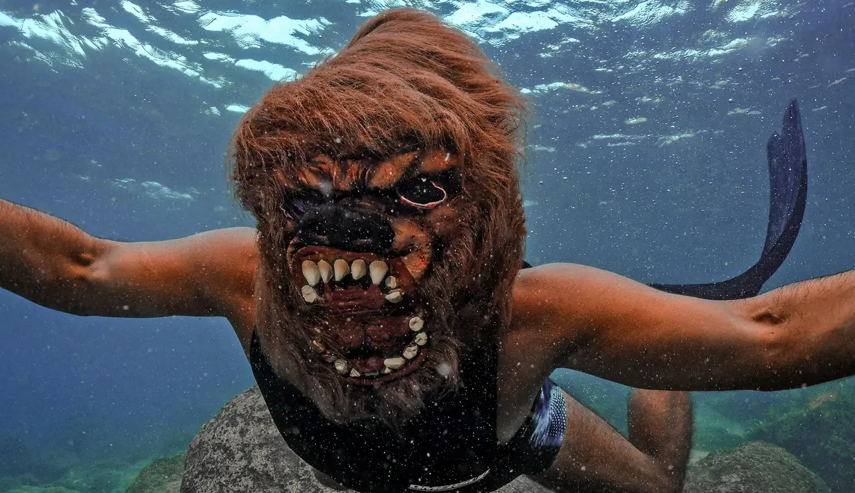 Seorang pria yang mengenakan kostum Halloween berenang di sepanjang pantai kota Batroun, Lebanon utara, pada Kamis (28/10/2021). Setiap tanggal 31 Oktober berbagai orang di belahan dunia biasa merayakan Halloween, hari yang identik dengan horor dan hal menakutkan. (Ibrahim Chalhoub/AFP)
