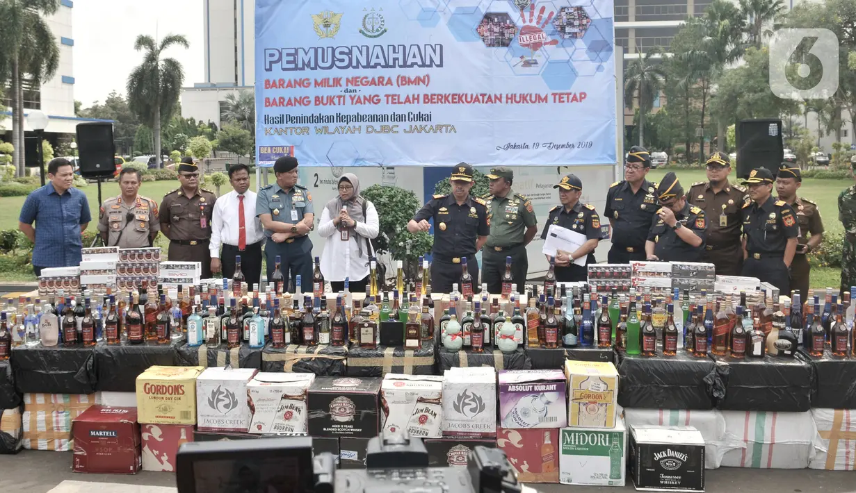 Petugas Bea dan Cukai memperlihatkan botol minuman keras dan rokok ilegal saat pemusnahan di Kantor Direktorat Bea Cukai, Jakarta, Kamis (19/12/2019). Dirjen Bea Cukai memusnahkan 2.777.114 batang rokok dan 14.719 botol minuman keras ilegal berbagai merek senilai Rp 6.462.090.500. (merdeka.com/Iqbal