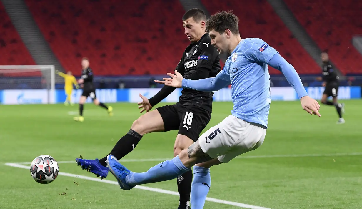 Bek Manchester City, John Stones (kanan) membuang bola dari ancaman bek Borussia Moenchengladbach, Stefan Lainer dalam laga leg kedua babak 16 besar Liga Champions 2020/2021 di Puskas Arena, Budapest, Selasa (16/3/2021). Manchester City menang 2-0 atas Gladbach. (AFP/Attila Kisbenedek)