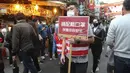 Seorang karyawan memegang tanda bertuliskan "Tolong pakai masker untuk melindungi Anda dan saya." dan berjalan-jalan di antara para pembeli untuk perayaan Tahun Baru Imlek di pasar Dihua Street di Taipei, Taiwan, Rabu (10/2/2021). (AP Photo/Chiang Ying-ying)