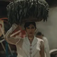 Potret pertama, Dian Sastrowardoyo tampil mengenakan kebaya modern warna putih dengan aksen transparan pada lengan panjangnya. Dipadukan aksesori keemasan dari bros, kalung, dan anting-anting. [@bramsky.bramsky]