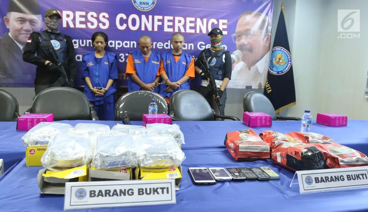 Petugas menunjukkan barang bukti ekstasi asal Jerman berserta ketiga tersangka saat rilis di Jakarta, Senin (4/3). BNNP DKI Jakarta menggagalkan penyelundupan 37.799 butir ekstasi asal Jerman. (Liputan6.com/Angga Yuniar)