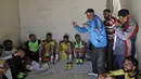 Seorang pelatih sepak bola tim lokal Suriah memberi arahan kepada pemainnya jelang pertandingan di stadion Raqqa, bekas ibu kota Suriah (16/4). Stadion ini juga pernah menjadi penjara untuk mereka yang ditawan ISIS. (AFP/Delil Souleiman)