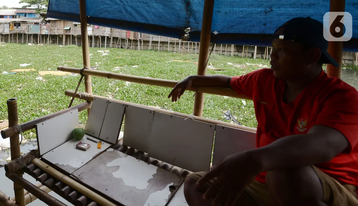 Warga duduk di pinggir kali Prancis di Dadap, Tangerang, Banten, Selasa (23/11/2021). Kali yang dipenuhi sampah dan eceng gondok (Eichhornia crassipes) menimbulkan bau tidak sedap bagi masyarakat sekitar dan membuat aliran menjadi terhambat. (merdeka.com/Imam Buhori)
