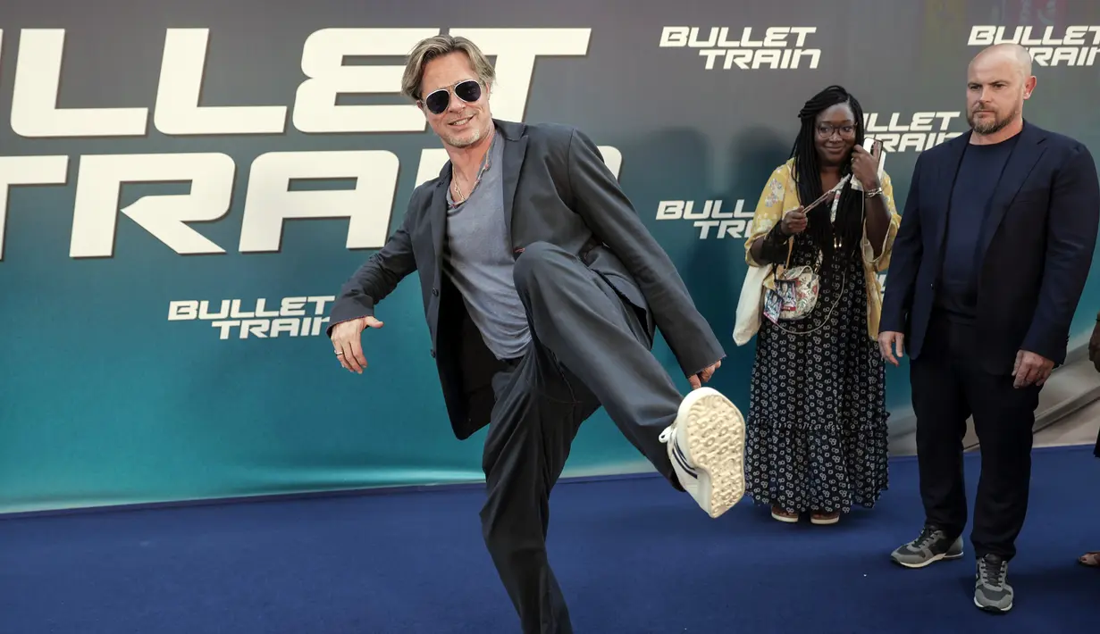 Brad Pitt bercanda dengan kameramen saat tiba pada pemutaran perdana film Bullet Train di Paris, Prancis, 18 Juli 2022. Brad Pitt mengenakan sepasang sepatu olahraga putih saat dia mengangkat kakinya ke arah fotografer sambil berjalan di karpet biru. (AP Photo/Lewis Joly)