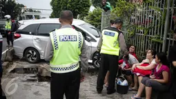 Polisi berjaga didekat mobil yang menabrak separator busway matraman arah kampung melayu, Jakarta, Sabtu (25/2). (Liputan6.com/Faizal Fanani)