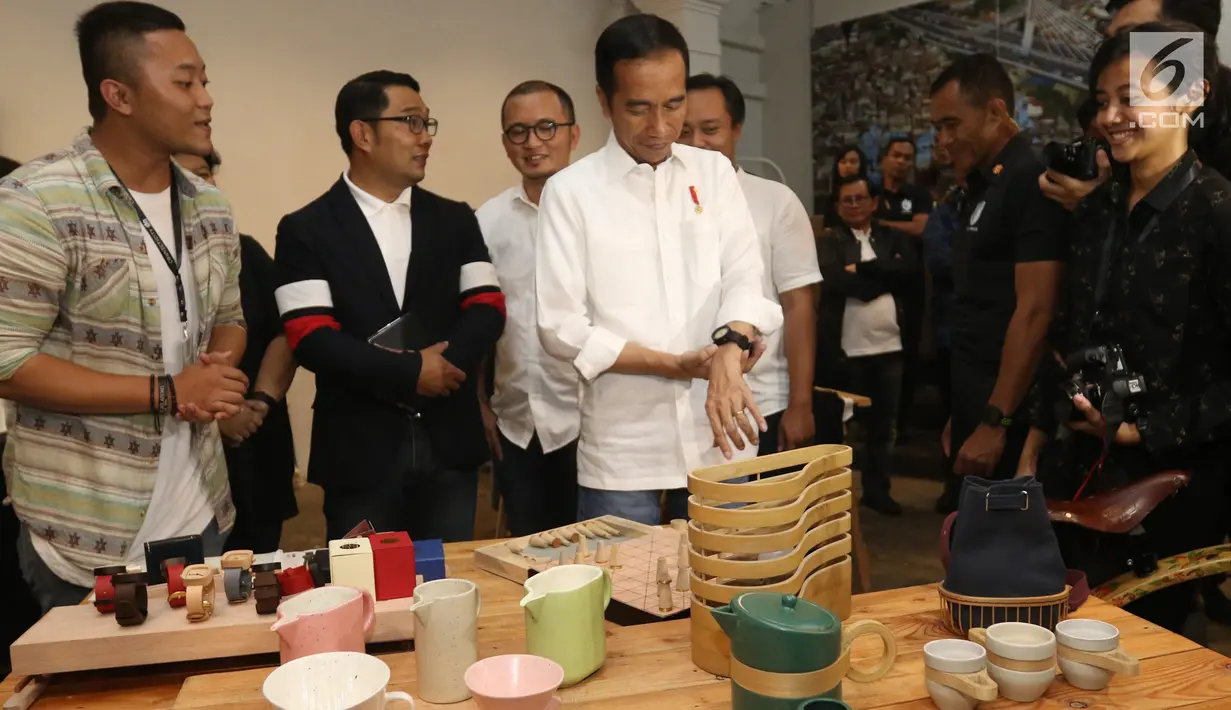 Calon Presiden Nomor Urut 01 Joko Widodo didampingi Gubernur Jawa Barat Ridwan Kamil (kedua kiri) mencoba memakai jam yang dipamerkan sebelum berdiskusi dengan masyarakat kreatif Bandung di Simpul Space, Bandung, Sabtu (10/11). (Liputan6.com/Angga Yuniar)