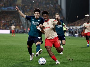 Penyerang Lens #09 Elye Wahi (kanan) berebut bola dengan bek Arsenal #18 Takehiro Tomiyasu pada laga matchday 2 Grup B Liga Champions 2023/2024 yang digelar di Stade Bollaert-Delelis, Rabu (4/10/2023) dini hari WIB. (Sameer Al-Doumy / AFP)