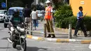 Pengendara melintasi manekin pria berseragam polisi lalu lintas di persimpangan jalan di Bangalore, India, Senin (16/12/2019). Dilengkapi dengan topi polisi, kemeja putih serta kacamata hitam, polisi manekin  itu siap “bertugas” di perempatan jalan yang kerap macet. (Manjunath KIRAN / AFP)