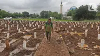 Petugas berjalan di antara makam jenazah dengan protokol COVID-19 di TPU Bambu Apus, Jakarta Timur, Selasa(16/2/2021). Pemangkasan petak makam di TPU Bambu Apus tersebut dilakukan agar bisa menampung lebih banyak jenazah, mengingat lahan pemakaman terbatas. (Liputan6.com/Herman Zakharia)