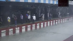 Orang-orang menunggu kereta sementara rel kereta api terendam banjir saat hujan lebat di Mumbai, India, Rabu (9/6/2021). Mumbai terendam banjir usai diguyur hujan lebat. (AP Photo/Rafiq Maqbool)