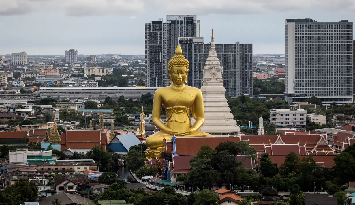<p>Patung Buddha raksasa setinggi 69 meter berdiri di kuil Wat Paknam Phasi Charoen di pinggiran Bangkok, Thailand pada Selasa (12/10/2021). Patung raksasa yang mulai dibangun tahun 2017 dan ukurannya setinggi gedung 20 lantai ini menghiasi langit kota metropolitan Bangkok. (Jack TAYLOR / AFP)</p>