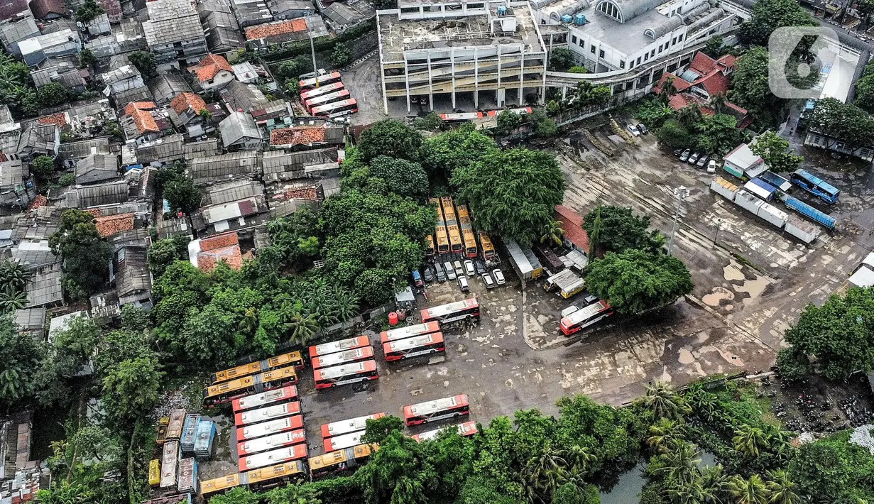 Pandangan udara puluhan bus Transjakarta saat terbengkalai di area Terminal Pinang Ranti, Jakarta Timur, Rabu (21/12/2022). Menurut petugas parkir setempat, sekitar 25 bus Transjakarta tersebut terbengkalai dan sudah tidak beroperasi sejak awal pandemi Covid-19. Beberapa bus pun terlihat berkarat dan tertutup pepohonan. (merdeka.com/Iqbal S. Nugroho)