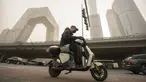 Seorang pria yang mengenakan masker mengendarai skuter di sepanjang jalan di kawasan pusat bisnis di Beijing, Rabu, 22 Maret 2023. (AP Photo/Mark Schiefelbein)