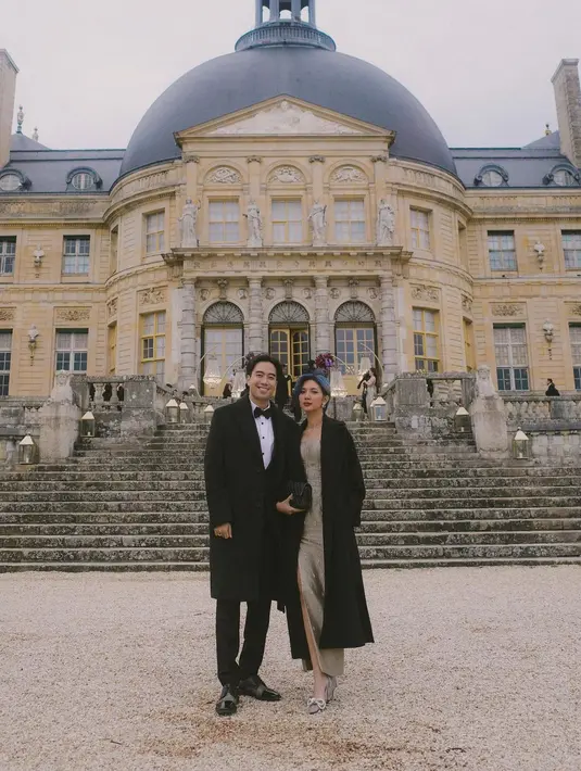 Yang menarik adalah Vidi dan Sheila bahkan menghadiri acara pernikahan intim yang diselenggarakan oleh Valencia Tanoesodbjo dan Kevin Sanjaya di Paris. Sempat berpose di depan gedung acara, Vidi tampil bak bangsawan dengan setelan jas, lengkap dengan long coat dan dasi kupu-kupu hitamnya. Sheila tampil cantik dengan dress panjang bernuansa keemasan yang ditumpuk dengan long coat hitam. Foto: Instagram.