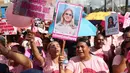 Seorang perempuan memegang poster bergambar mantan Ibu Negara Venezuela, Cilia Flores, saat mengikuti pawai yang diselenggarakan pemerintah untuk meningkatkan kesadaran terhadap kanker payudara dalam rangka Bulan Peduli Kanker Payudara atau Pink Month di Caracas, Venezuela, Kamis (22/10/2026). (AP Photo/Pedro Mattey)