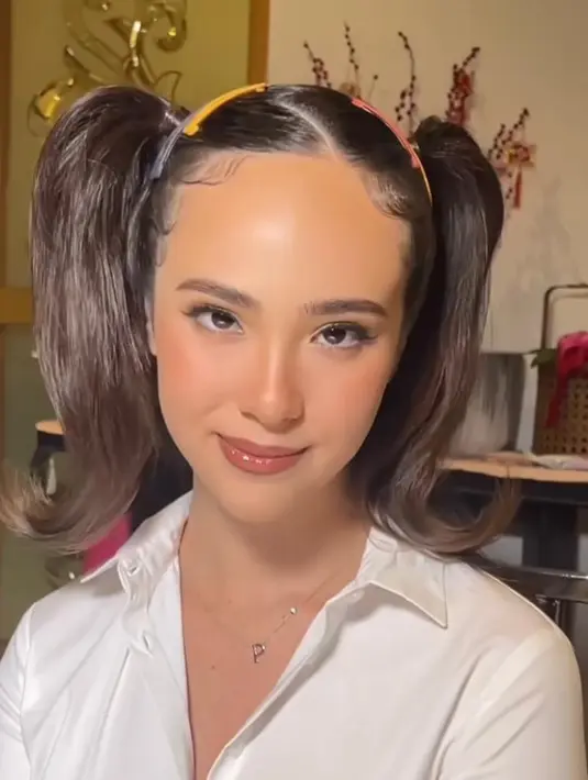 Wajahnya dipoles makeup natural yang flawless. Sementara rambutnya ditata pigtails dan dipermanis dengan aksesori jepit rambut warna-warni. [@pammybowie/@@makeupbycla]