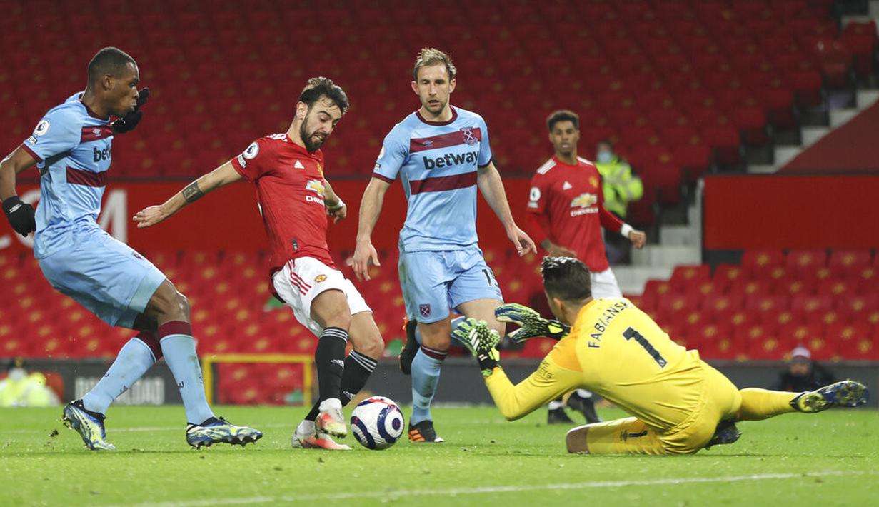Gelandang Manchester United, Bruno Fernandes, berebut bola dengan kiper West Ham United, Lukasz Fabianski, pada laga Liga Inggris di Stadion Old Trafford, Minggu (15/3/2021). Setan Merah menang dengan skor 1-0. (AP/Clive Brunskill,Pool)