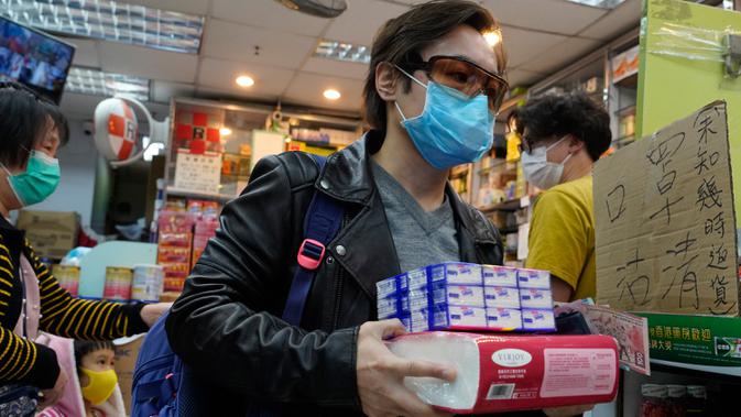 Seorang pria dengan mengenakan masker membawa kertas tisu ang dibelinya di apotek di Hong Kong, Kamis (6/2/2020). Di tengah kelangkaan masker wajah untuk melindungi terhadap wabah virus corona, tisu toilet tiba-tiba juga menjadi salah satu barang yang langka di Hong Kong. (AP/Vincent Yu)