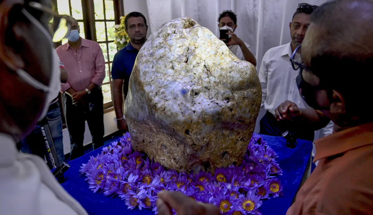 Orang-orang melihat permata yang diklaim sebagai safir biru korundum alami terbesar di dunia Bernama 'Queen of Asia', di Horana, sekitar 45 km dari Kolombo, Sri Lanka pada 12 Desember 2021. Beratnya 310 kg, ditemukan di lubang pencarian permata sekitar tiga bulan lalu. (Ishara S. KODIKARA / AFP)
