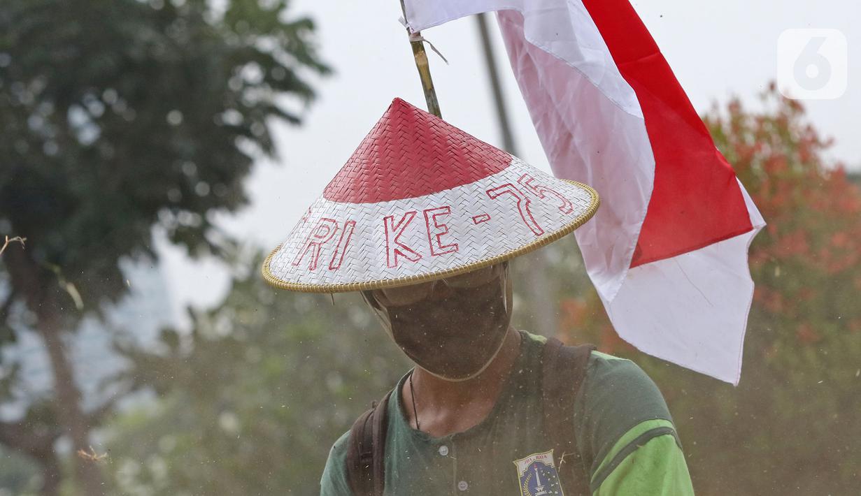 Petugas Pertamanan dan Kehutanan Kota Jakarta Pusat mengenakan atribut kemerdekaan saat memotong rumput di TPU Karet Bivak, Jakarta, Minggu (16/8/2020). Para petugas bekerja dengan mengenakan atribut kemerdekaan dalam rangka menyambut HUT ke-75 RI. (Liputan6.com/Herman Zakharia)