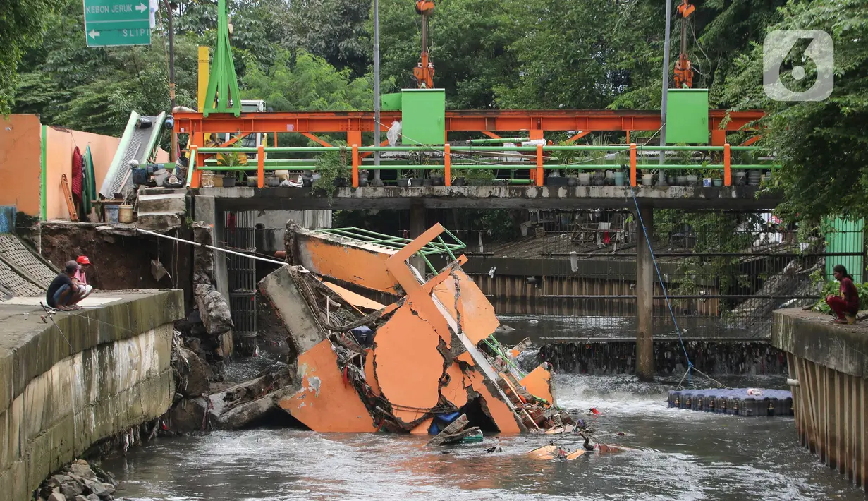 Warga melihat pos pantau Pintu Air yang rubuh di wilayah Palmerah, Jakarta, Selasa (6/2/2024). (Liputan6.com/Herman Zakharia)